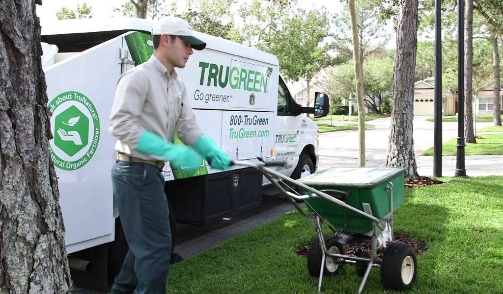 a TruGreen worker fertilizing a lawn